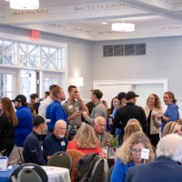 A large amount of people in the GVSU Alumni House & Visitor Center listening to a speech about rowing